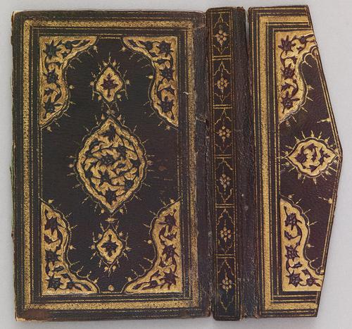 Outer cover of a dark-brown Turkish book binding with flap. There is a central gilt embossed medallion with pendants and corners on the cover. The flap of the book binding has a smaller version of the central medallion. The spine of the book binding has a repetition pattern of smaller floral pendants which are also gilt embossed.