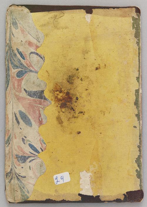 Interior of a bookbinding over, yellow paper pasted on top with a small section of marbled paper on the right side.
