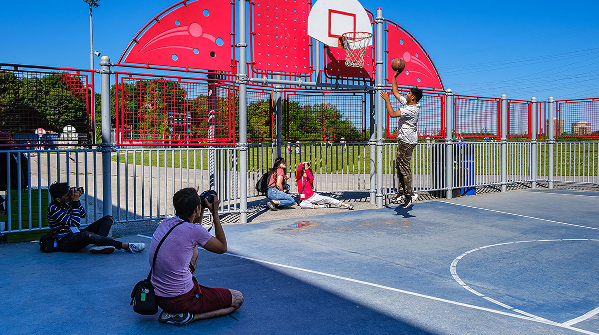 A student photographer sitting on the floor taking a picture of a playground.