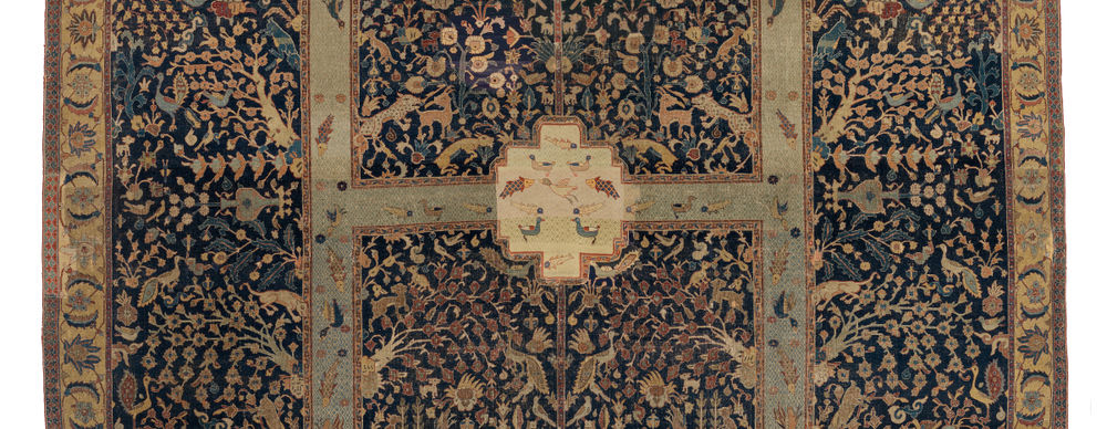 A detail view of a Persian carpet woven with plants, animals, birds, and fish