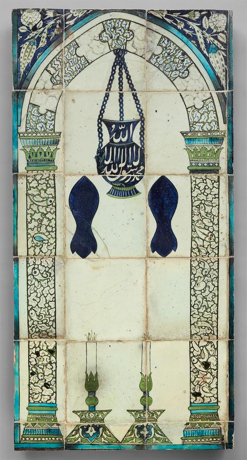A panel of 18 tiles showing an arch supported by decorated green, blue, and white columns. Between them are two large candlesticks. A blue lamp with a white inscription hangs from the top, and two dark blue footprints float below. Outside the arch are flower motifs on a blue background.