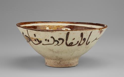 Side view of a circular bowl decorated in a brown paint over a cream background. The base is small and raised. The rim of the bowl is decorated in bands of white and brown. The exterior is decorated simply with verses of poetry.