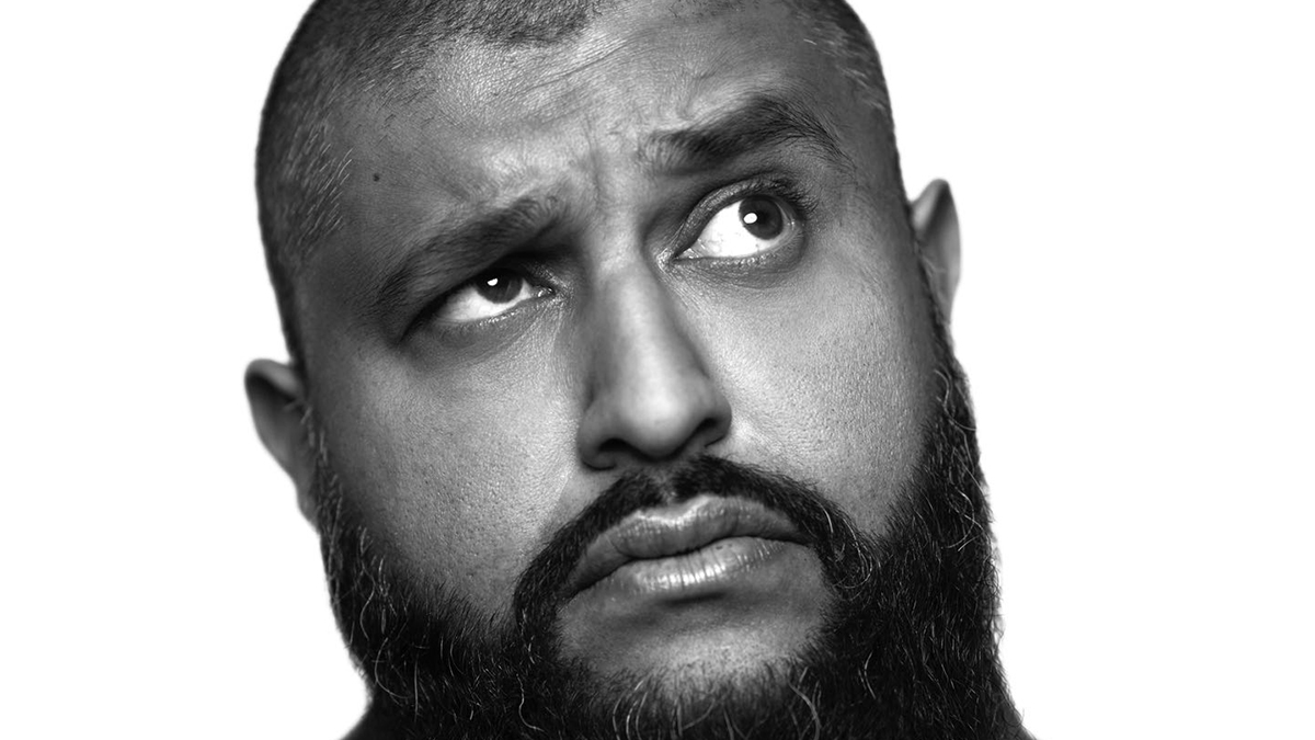 Comedian Azhar Usman’s looks up to the corner with a serious expression in a black and white headshot.