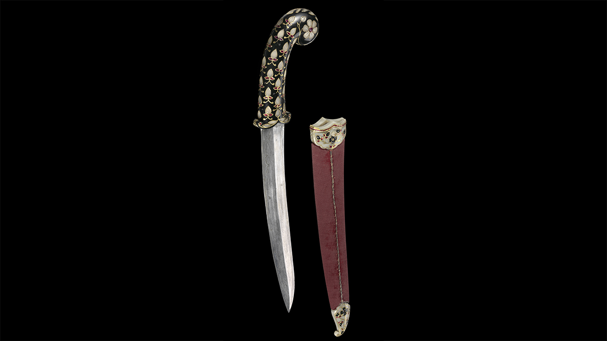 Steel dagger with a ruby-studded jade hilt beside its wooden scabbard, which is set with jade, gold, and rubies.