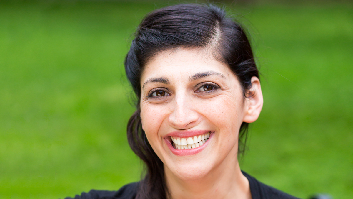 A close-up of Zahra Noorbakhsh smiling against a green backdrop. 