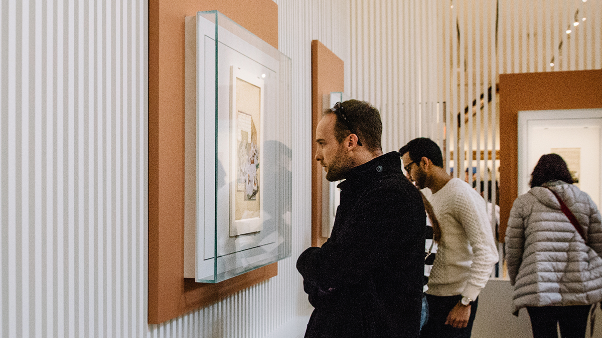 A man looks closely at a folio on the wall in the Museum’s Permanent Collection gallery.