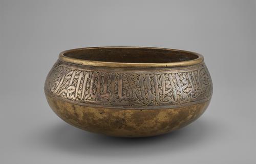 This round-bottomed brass bowl with bulging sides was raised from a single sheet of brass, with Arabic inscription running around the exterior of the bowl.