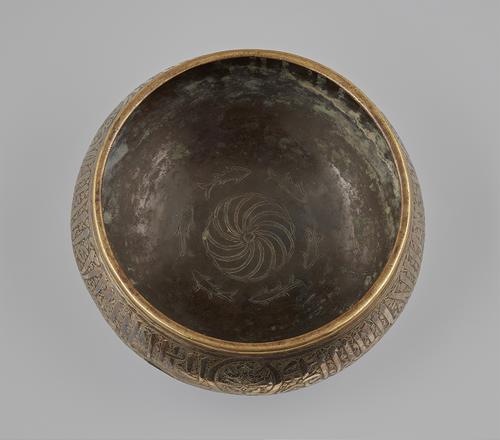 This round-bottomed brass bowl with bulging sides was raised from a single sheet of brass. View of inside where there are 6 engraved fish in a circle within the bowl would have appeared to wriggle and swim as the water splashed over them.