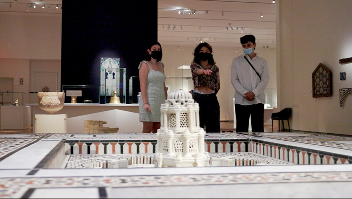 Three students wearing face masks gazing upon a fountain in the Aga Khan Museum's Collection Gallery.