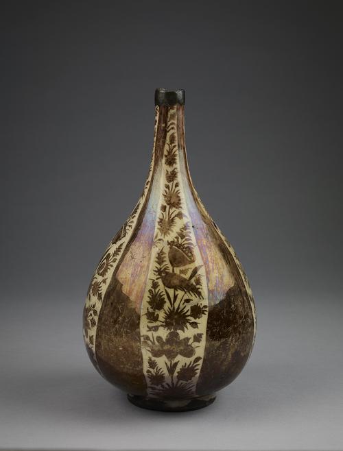 Lustre bottle, decorated in brown against a cream-coloured background. On the exterior, the surface is divided into four panels of foliate decoration separated by four massive cypress trees.
