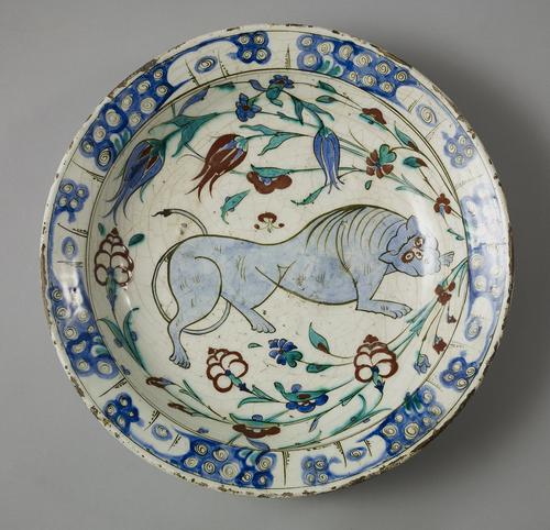 Dish rounded form, decorated in underglaze cobalt blue, viridian green and relief red, outlined in black, with a lion surrounded by tulips and hyacinth flowers, the rim with circular and spiral motifs, the reverse with alternating floral motif.