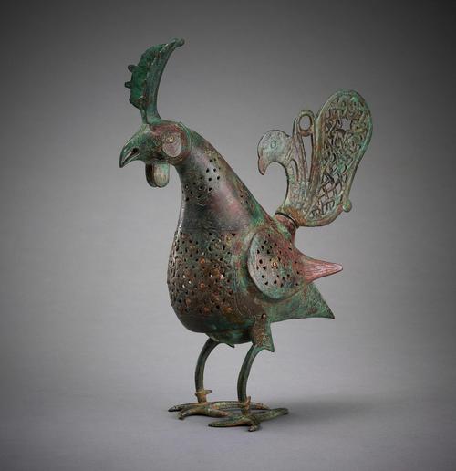 Cast in bronze, this bird-shaped object once served as an incense burner. The bird has decorative holes pierced in its neck, stomach, wings, and tail. The tail takes the shape of a miniature bird.