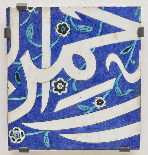 Square ceramic tile decorated with arabic calligraphy and florals.