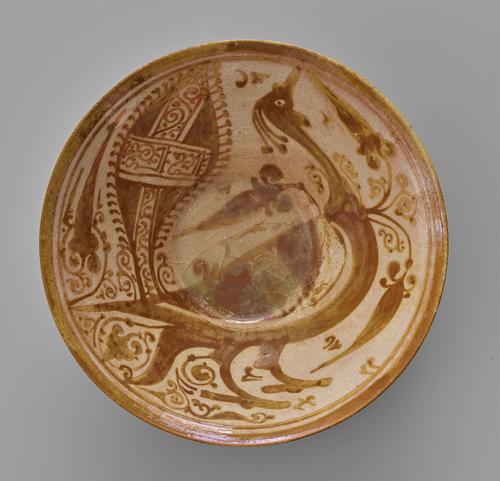 Beige bowl with brown designs. The bowl has flaring sides and slightly splayed rim, interior featuring scrolling floral motifs around the large figure of a peacock