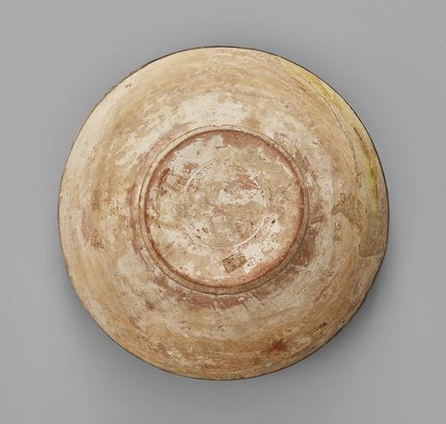 Bottom side of a beige bowl, view of the round foot.