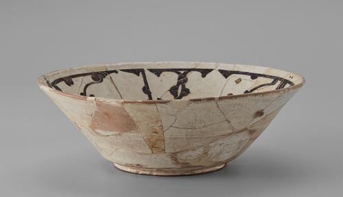 Side of a bowl, with white slip over the reddish body is decorated with a dark brown and red inscription on the sides. Exterior sides show cracking and restoration.