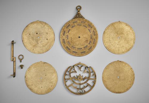 Astrolabe disassembled to see the backs of all plates, laid out in a grid.