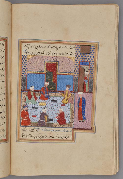  Painting within a rectangular border of blue, gold, green, and red, with script across the top and bottom. Six sages kneel on a flowered carpet, conversing with one another. Another sage is standing, and another enters the room.   
