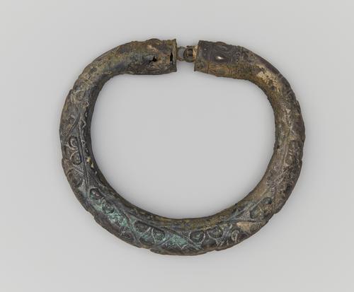 One of two silver arm bracelets, engraved, the top bracelet shows the clasp or connection and top. Showing signs of corrosion on all sides.