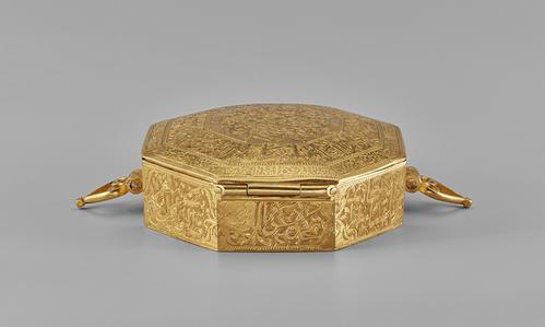 Back view of the Gold Qur’an case open, View of the palmette-shaped loops on either side and the back hinge of the lid.