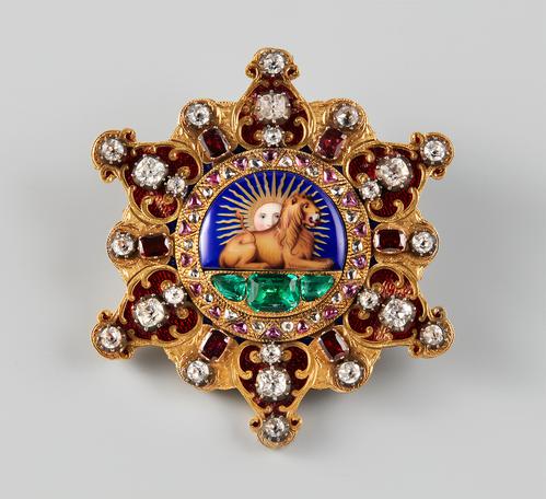 In the form of a six-pointed openwork star, set with diamonds and other precious gemstones, predominantly rubies. The central enameled medallion features a lion laying down with a sun rising behind its back in the centre.