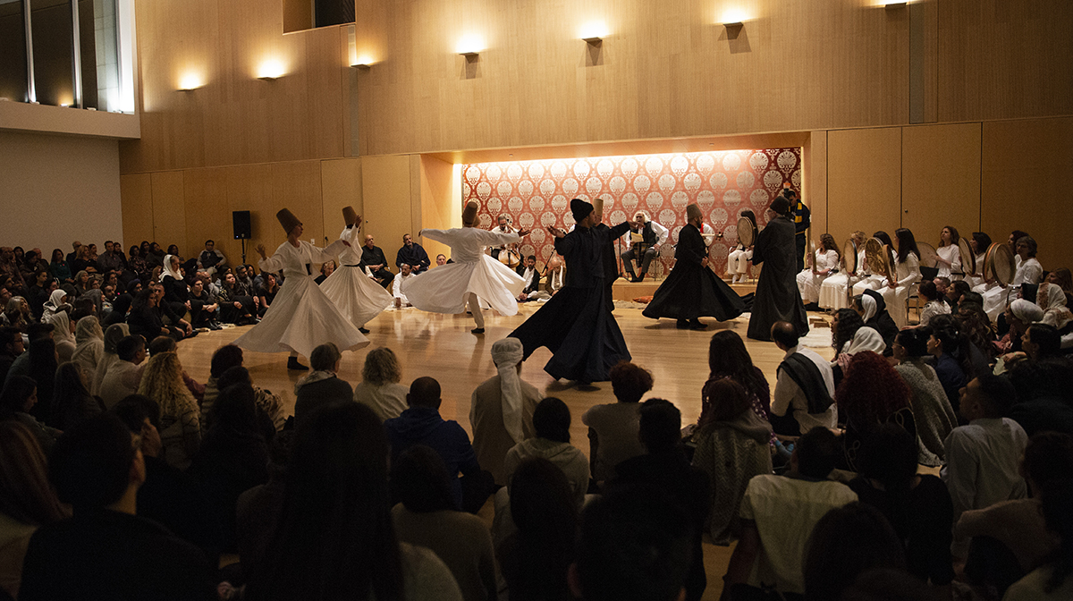 Whirling dervishes twirl onstage amidst a crowd of onlookers in the Ismaili Centre, Toronto