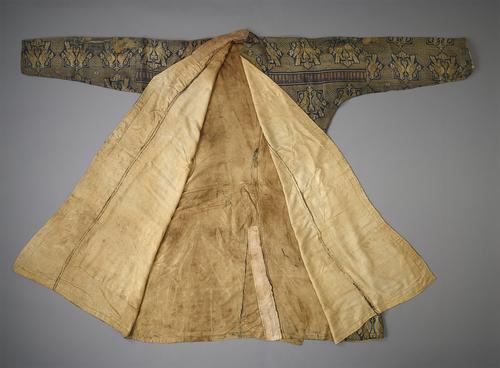 Silk robe, laid flat with the arms out to the side and folded open to show the cream silk lining. The robe is woven with a repeating gold-and-blue pattern of two birds facing each other inside of a geometric star. There is a horizontal band extending from shoulder to shoulder.   