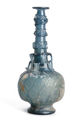 Blue glass bottle of compressed globular form on a spreading foot with a kick base and long thin cylindrical neck leading to a flanged mouth with a trellis pattern of tear-shaped drops.