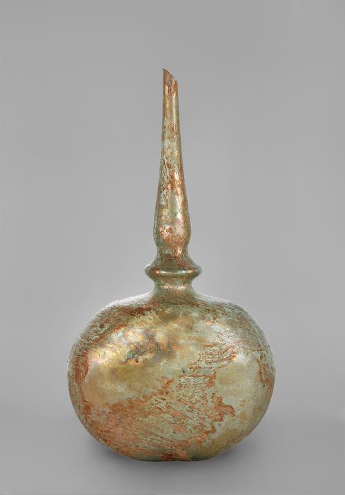 Coloured gold, pale green glass with a globular body that has been flattened on two sides and a long tapering neck with a bulge near its base.