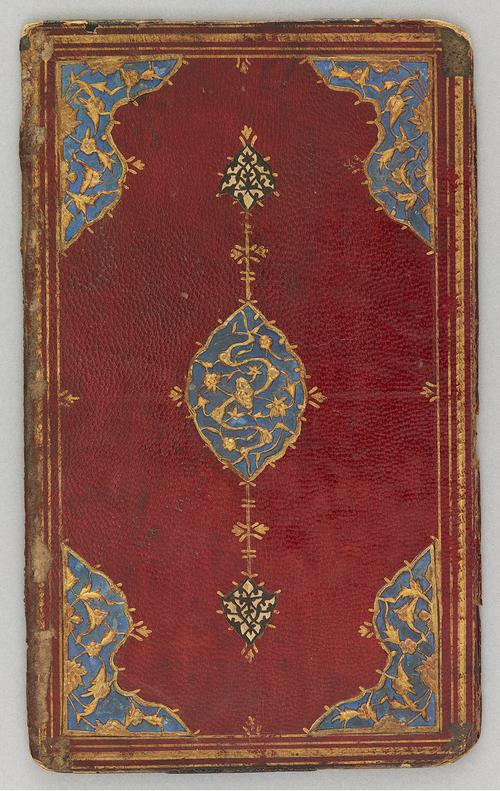 The red leather bookbinding interior cover. The cornerpieces and central oval medallion with pendants have a blue ground overlaid with gold gilded filigree in a design of large flowers and leaves. 