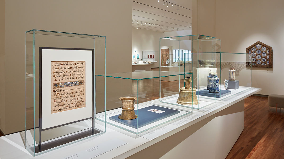 Museum collection gallery, featuring multiple objects on a large rectangular showcase under four glass top covers.