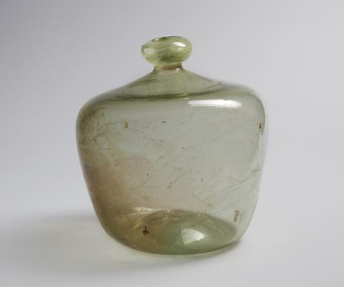 Short Glass bubble shaped bottle with narrow rim, rounded mouth, blown from colourless glass with a greenish tinge.