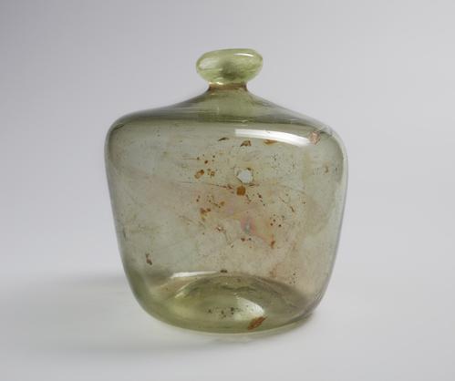 Short glass bubble shaped bottle with narrow rim, rounded mouth, blown from colourless glass with a greenish tinge. Right side of the shoulder of the bottle is higher than the left.