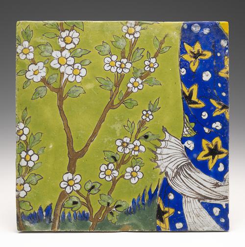 Two ceramic square tiles depicting a seated figure against a background of flowers, trees and greenery, holding a notebook in one hand and dipping his quill into his inkpot with the other. 