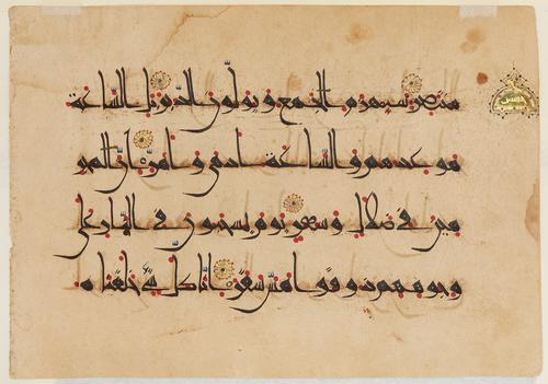 A rectangular folio with four verses in black ink and punctuated by red dots to assist in reading. Five gold rosettes with blue centres indicate the beginning of each verse, and the ending of each group of ten verses is marked by a larger, golden medallion (upper right).